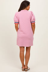 woman wearing a pink maternity dress with puff sleeves and striped details on the sleeves, showing her back
