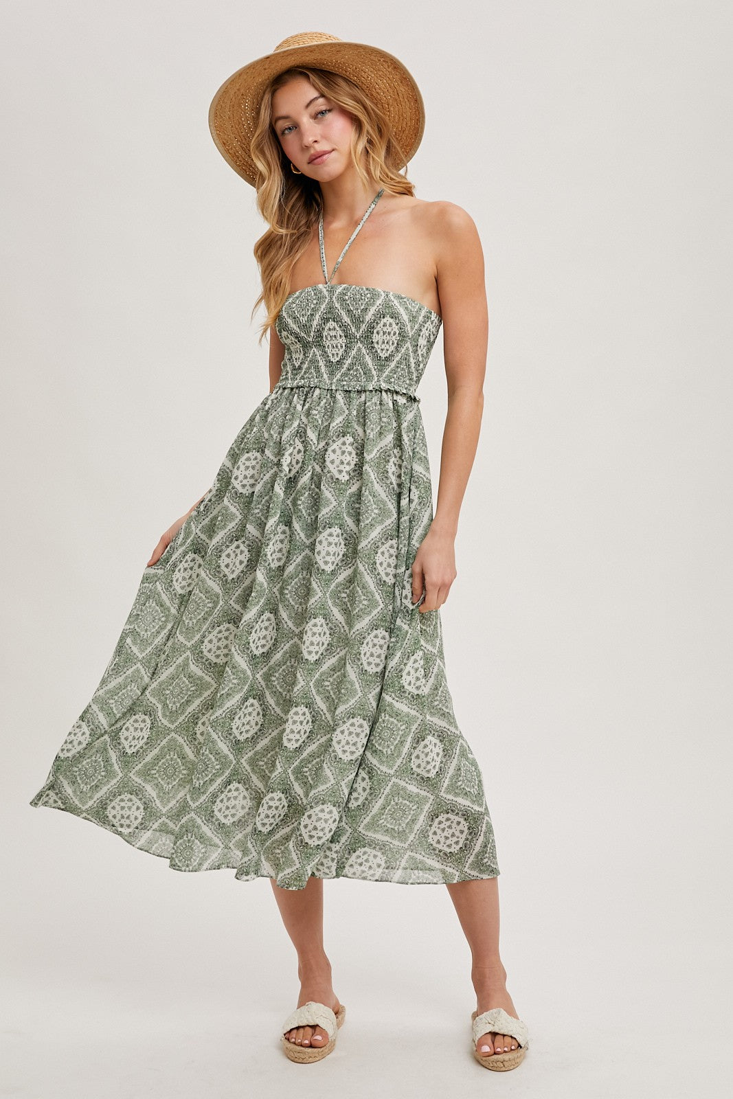 woman wearing a green patterned strapless maxi dress with a halter neck and a wide-brimmed hat