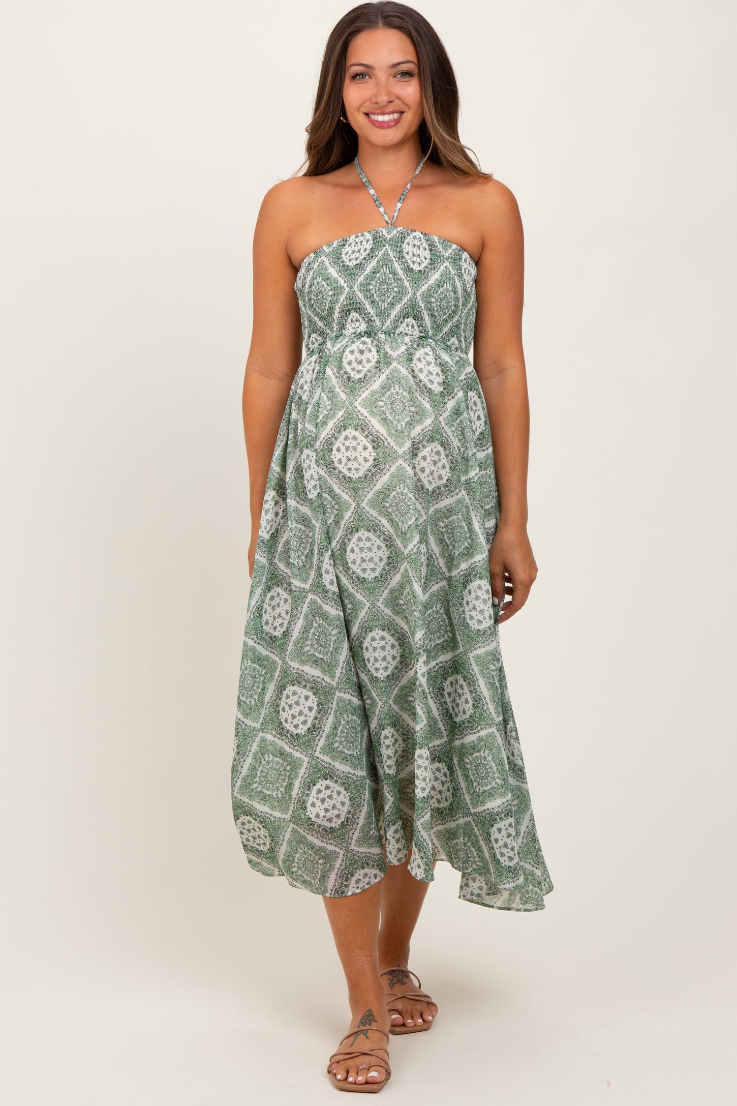 woman wearing a green printed strapless maternity dress, featuring a flowing silhouette and a halter neck style