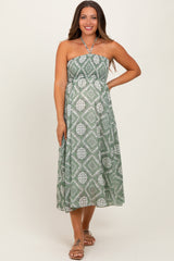 woman wearing a green strapless maxi maternity dress with a geometric print and a tie neckline, showing a baby bump