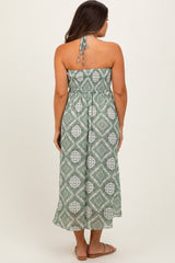 woman wearing a green patterned strapless maternity maxi dress, showing a baby bump from the back
