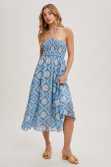 woman wearing a light blue patterned halter neck dress with a flowing skirt and minimal accessories