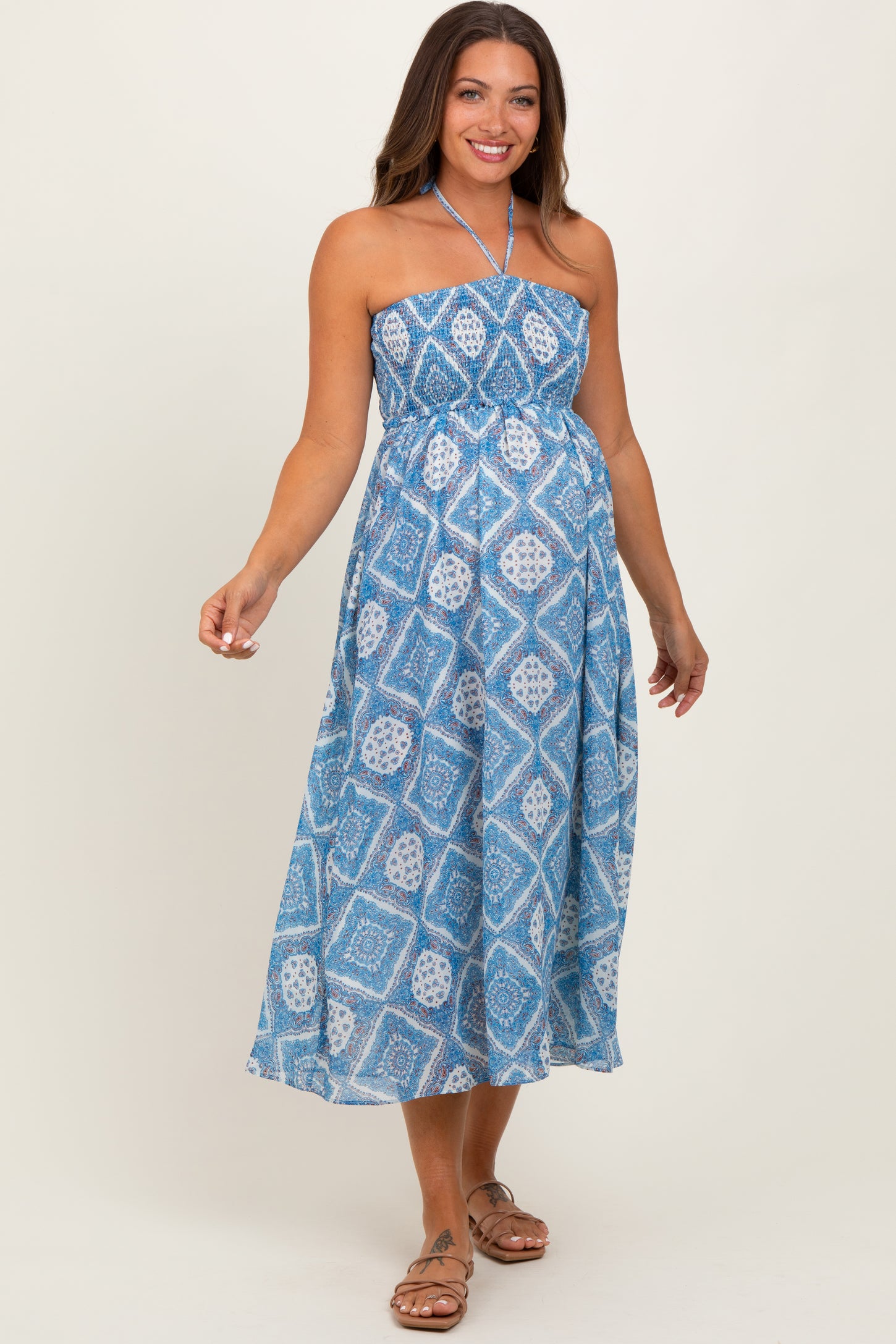 woman wearing a blue patterned strapless maternity dress with a flowing midi skirt and a baby bump visible