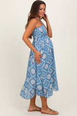 woman wearing a blue patterned maternity maxi dress with a fitted bodice and flowing skirt, showing baby bump