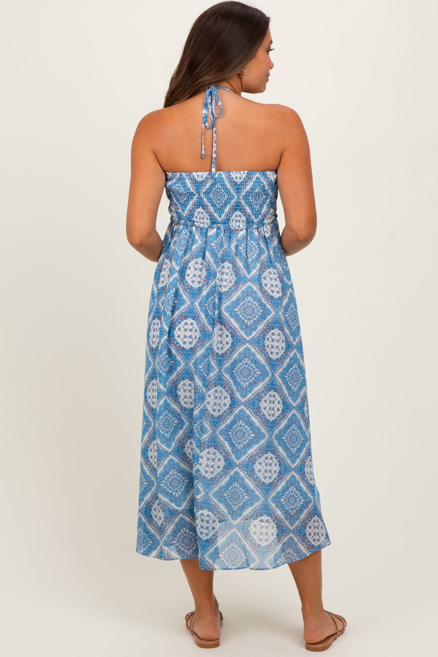 woman wearing a blue patterned maternity maxi dress with a halter neckline and a flowy silhouette