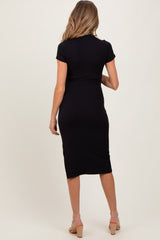 woman wearing a black ribbed maternity dress with short sleeves, showing a fitted silhouette from the back