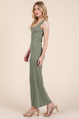 woman wearing a green sleeveless maxi dress and tan heeled sandals, posing sideways