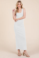 woman wearing a white sleeveless maxi dress with a fitted silhouette and a scooped neckline