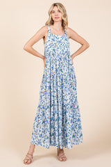 woman wearing a light blue maxi dress with floral print and tiered styling, standing with hands on hips