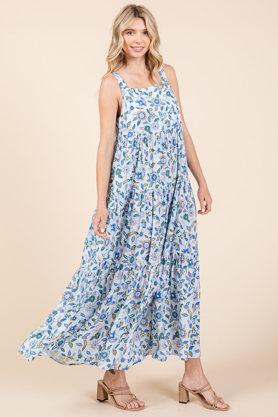 woman wearing a flowy light blue floral maxi dress with adjustable straps and tiered skirt