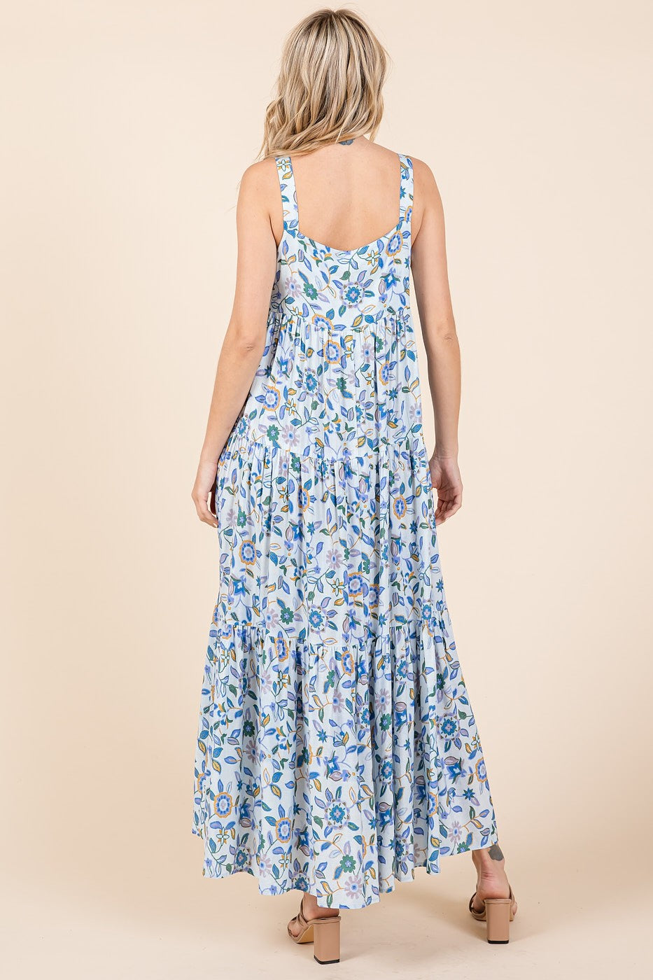woman wearing a blue and white floral maxi dress with a tiered skirt, viewed from the back