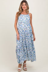 woman wearing a blue floral maternity maxi dress with a tiered skirt and adjustable straps