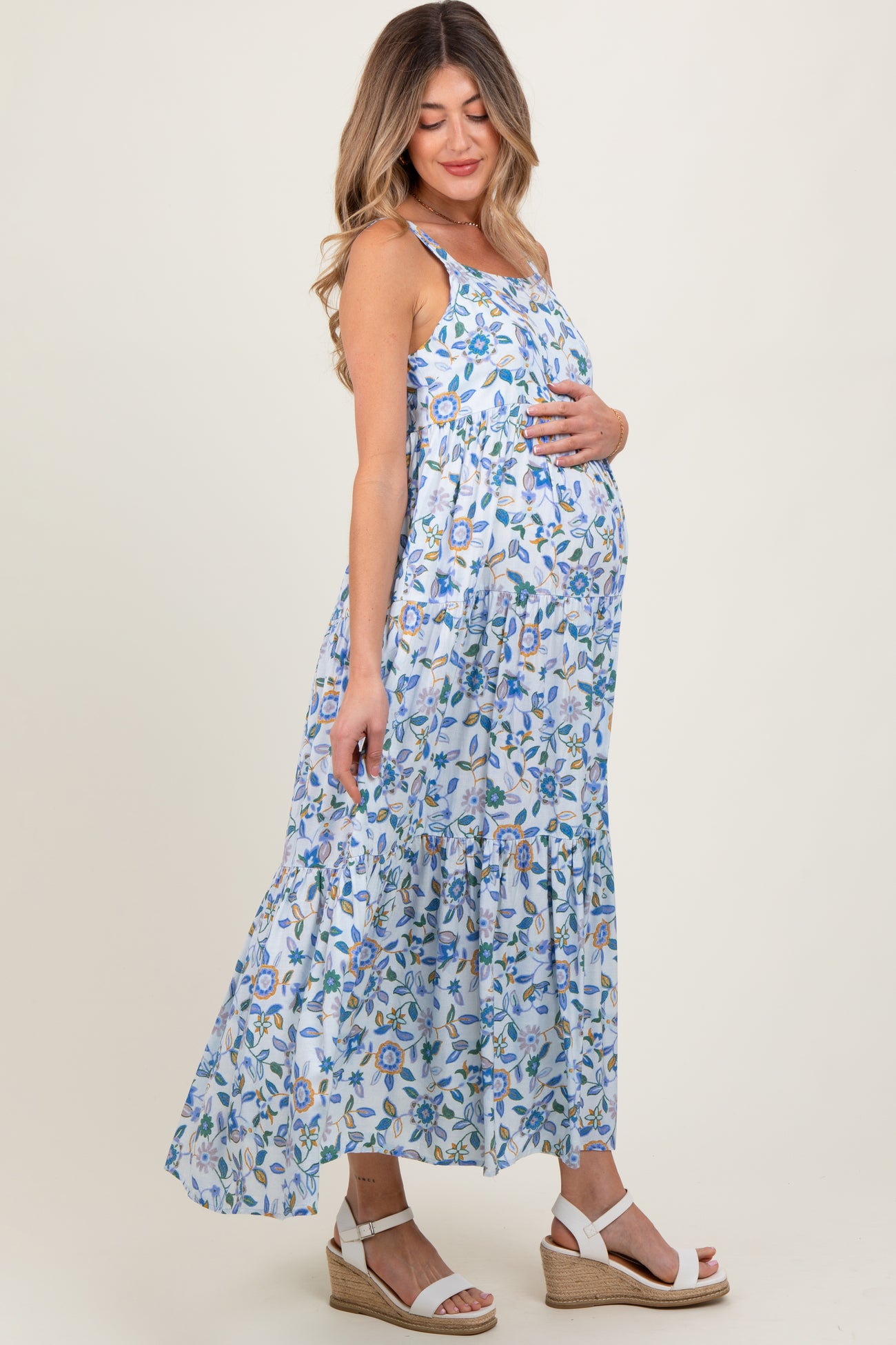 woman wearing a floral maternity maxi dress with spaghetti straps and a visible baby bump