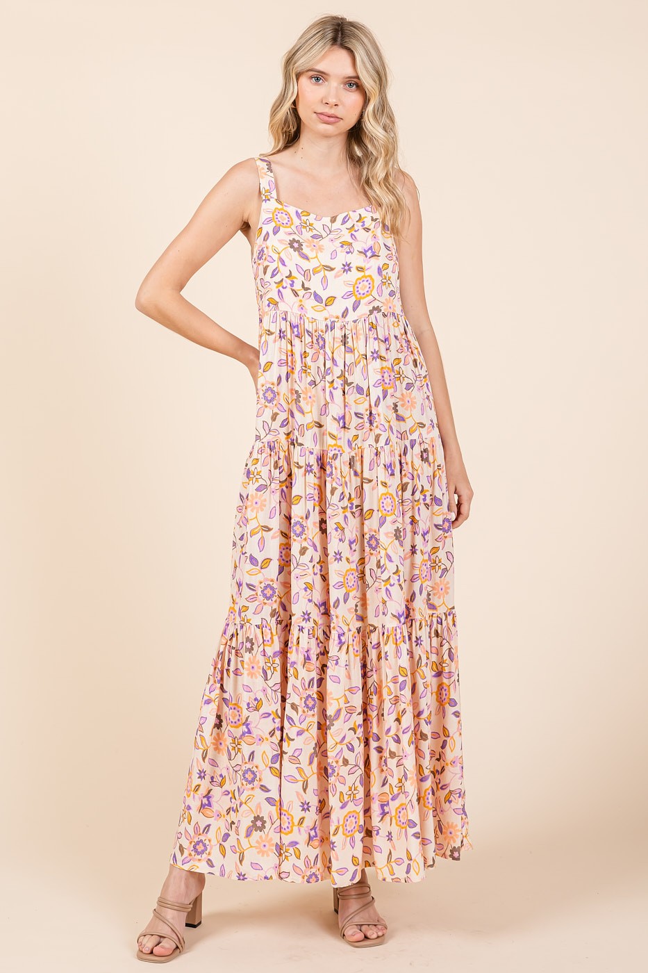 woman wearing a floral print maxi dress in pink and yellow with tiered details and spaghetti straps