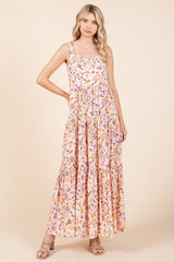 woman wearing a floral print maxi dress in pink and yellow with tiered details and spaghetti straps