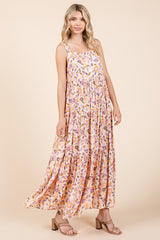 woman wearing a floral pink maxi dress with thin straps and a tiered design in a light, flowy fabric