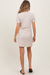 woman wearing a light beige maternity t-shirt dress, showing a simple and comfortable back view