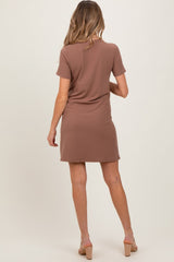 woman wearing a brown short sleeve maternity dress, shown from the back, with a relaxed fit and knee-length style