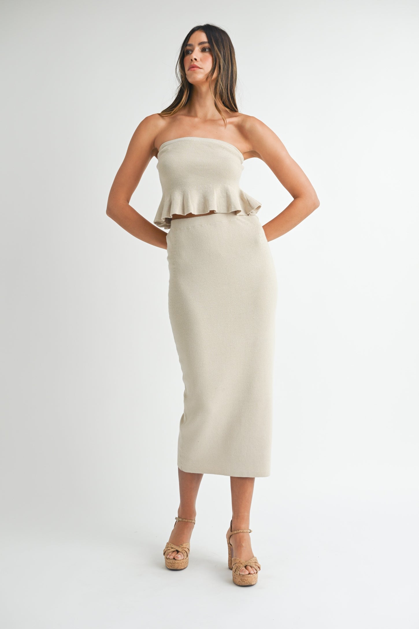 woman wearing a beige strapless ribbed two-piece set with a ruffled crop top and a midi skirt