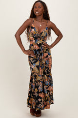 woman wearing a floral maxi dress with a deep neckline and spaghetti straps, posing with her hands on her hips