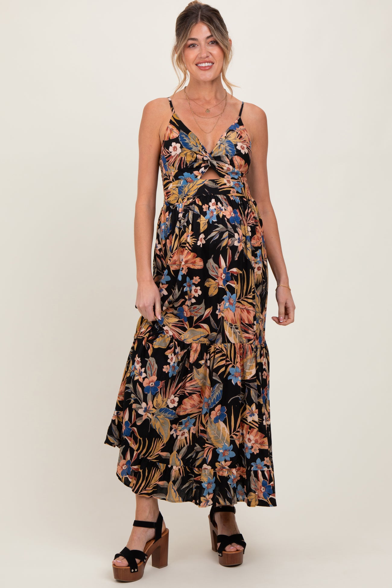 woman wearing a black floral maternity maxi dress featuring adjustable straps and a fitted bodice with a baby bump visible