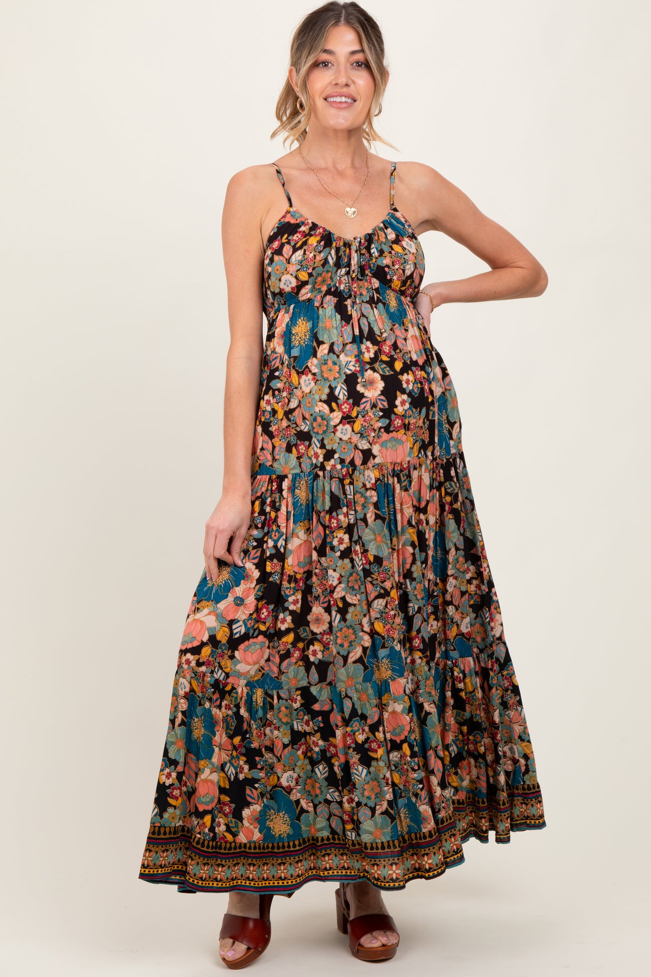 woman wearing a black floral maxi maternity dress with adjustable straps and a flowy skirt, showcasing her baby bump