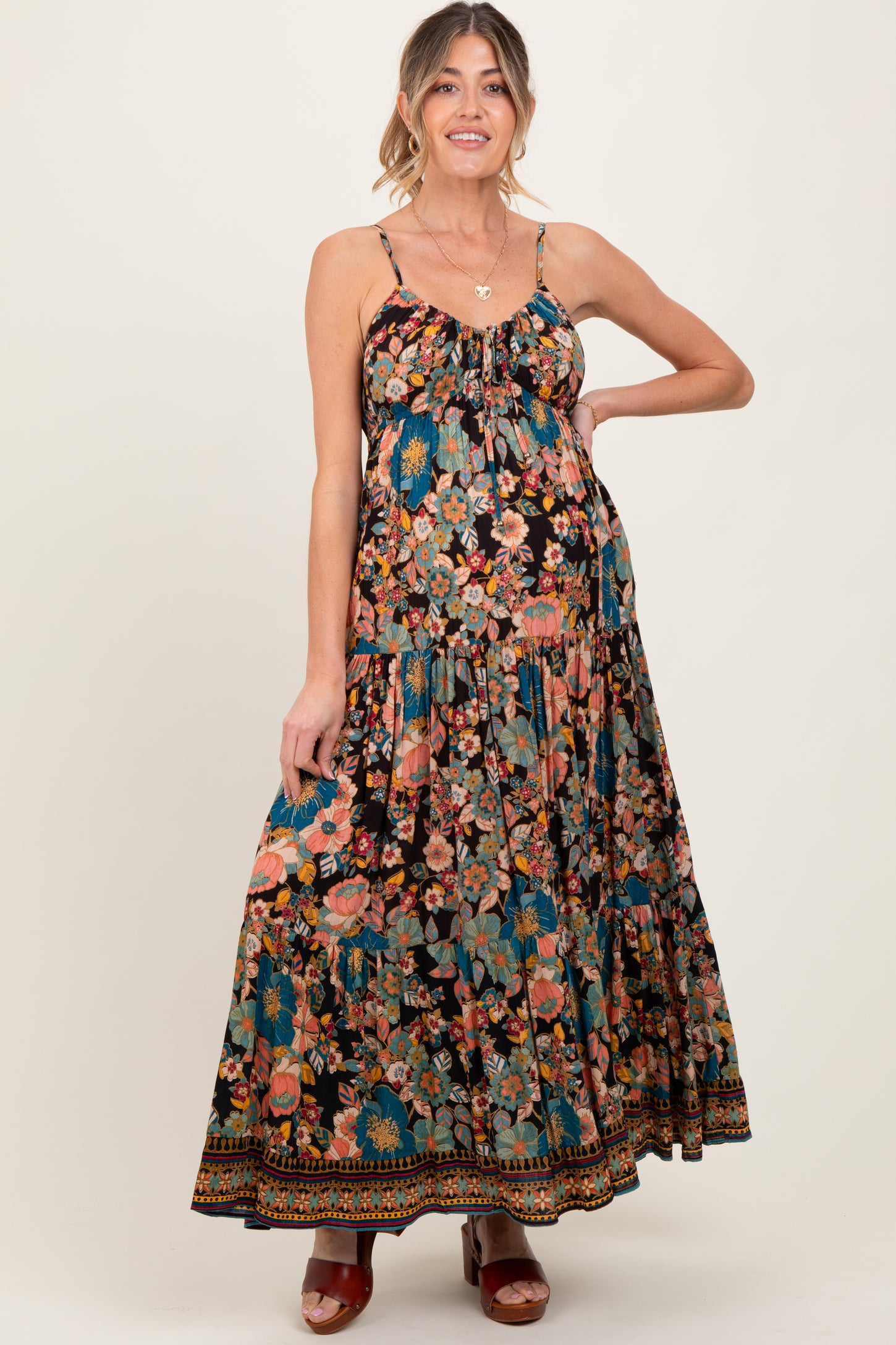 woman wearing a black floral maxi maternity dress with adjustable straps and a flowy skirt, showcasing her baby bump