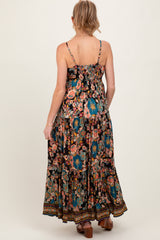 woman wearing a black floral maternity maxi dress with adjustable straps and a tiered skirt, showing her back