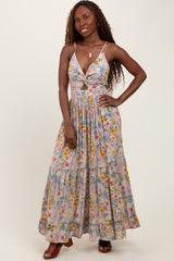 woman wearing a floral maxi dress with a deep V-neck and a tiered skirt, posing with a smile