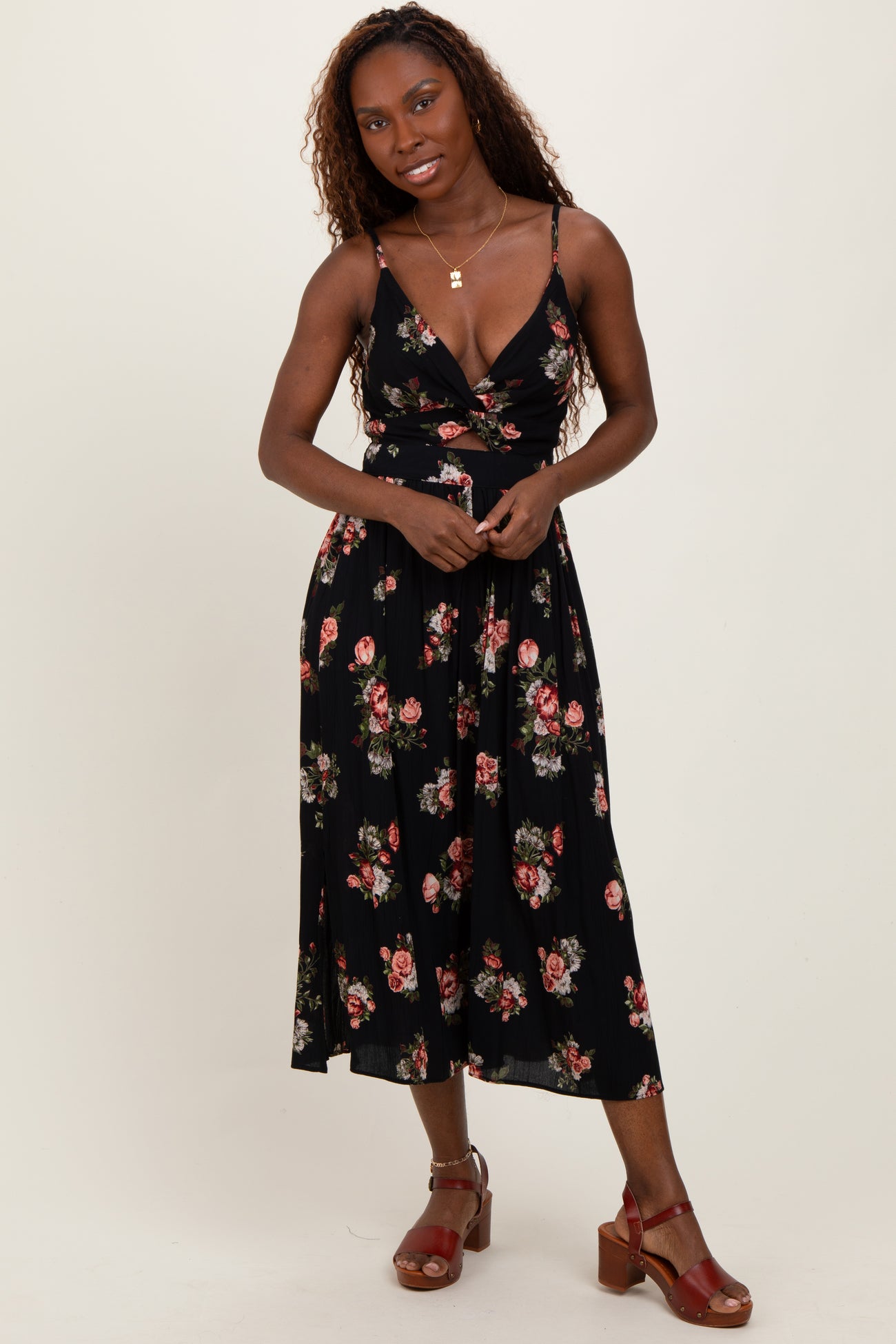woman wearing a black floral midi dress with a plunging neckline and spaghetti straps