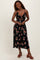 woman wearing a black floral midi dress with a plunging neckline and spaghetti straps