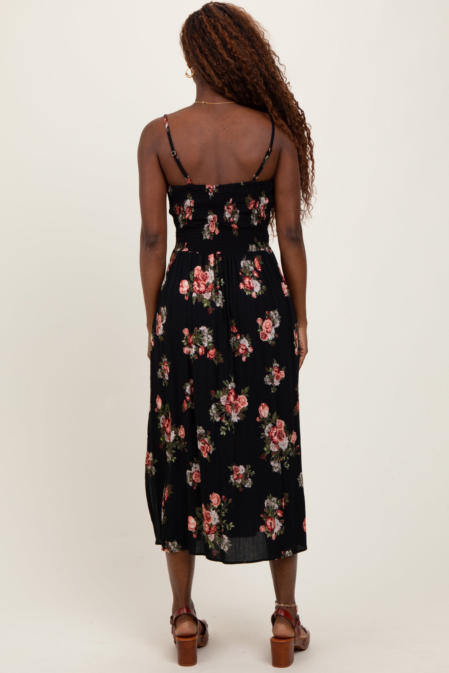 woman wearing a black floral midi dress with a smocked bodice and thin straps, seen from the back