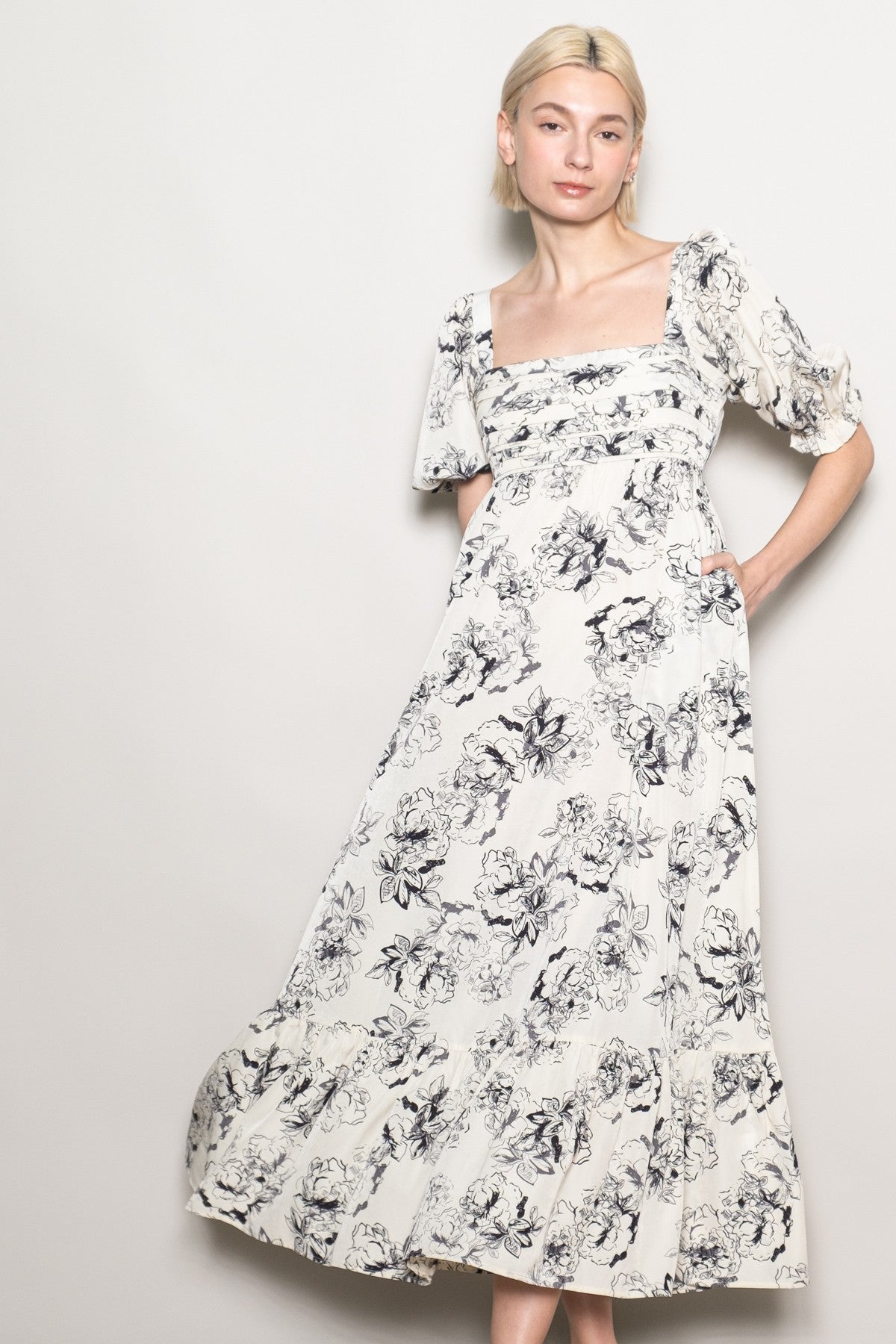 woman wearing a white floral print maxi dress with puff sleeves and a ruffled hem.