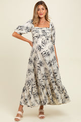 woman wearing a floral maternity maxi dress with a square neckline and puff sleeves, showcasing her baby bump