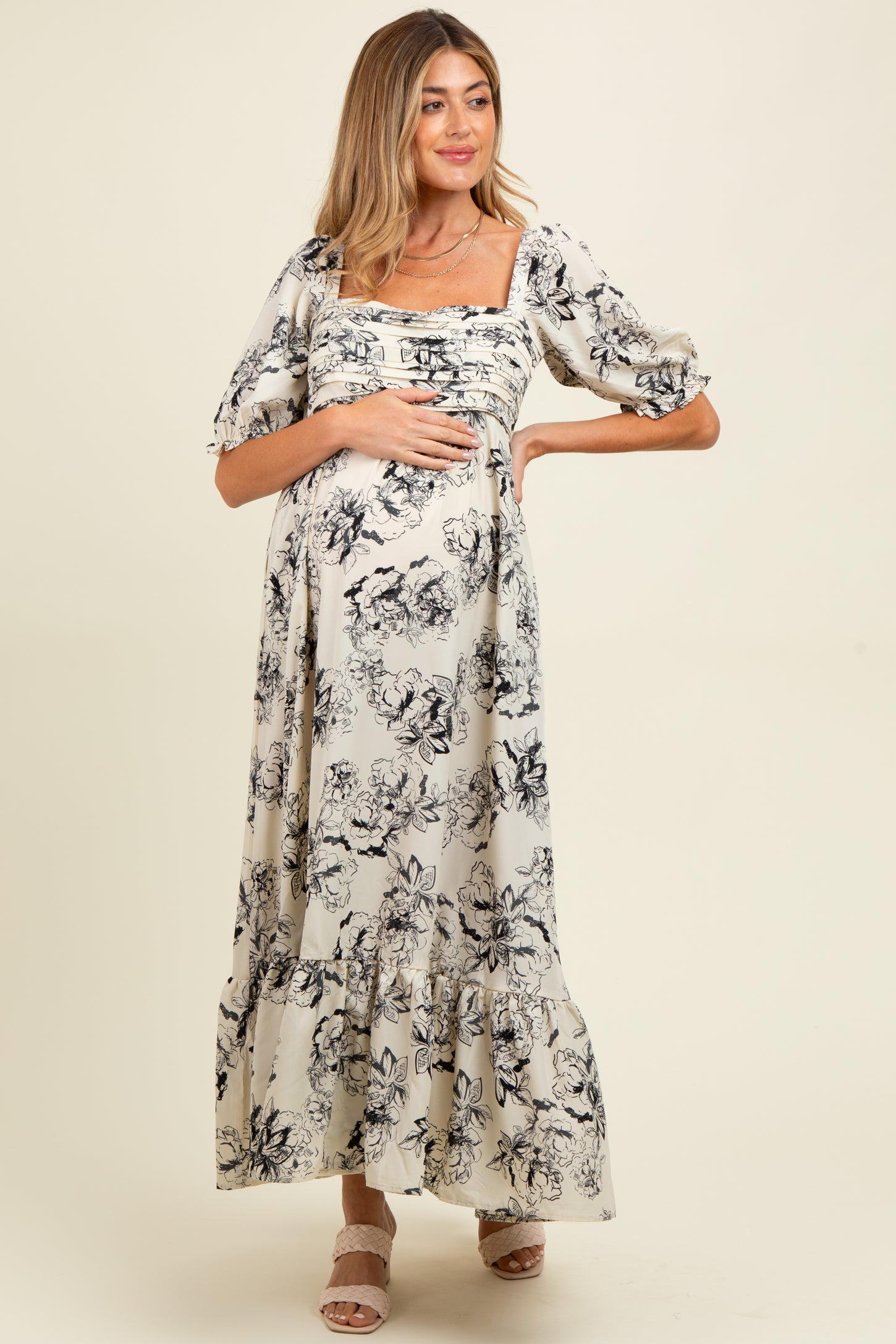 woman wearing a black and white floral print maternity maxi dress and holding her baby bump
