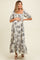 woman wearing a black and white floral print maternity maxi dress and holding her baby bump