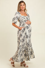 woman wearing a floral print maternity maxi dress with puff sleeves and a baby bump, posing with hands on her belly