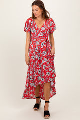 woman wearing a red floral wrap dress with short sleeves and a high-low hemline, styled with black heeled sandals