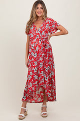woman wearing a red floral print maternity maxi dress with short sleeves and a tie waist, showing her baby bump