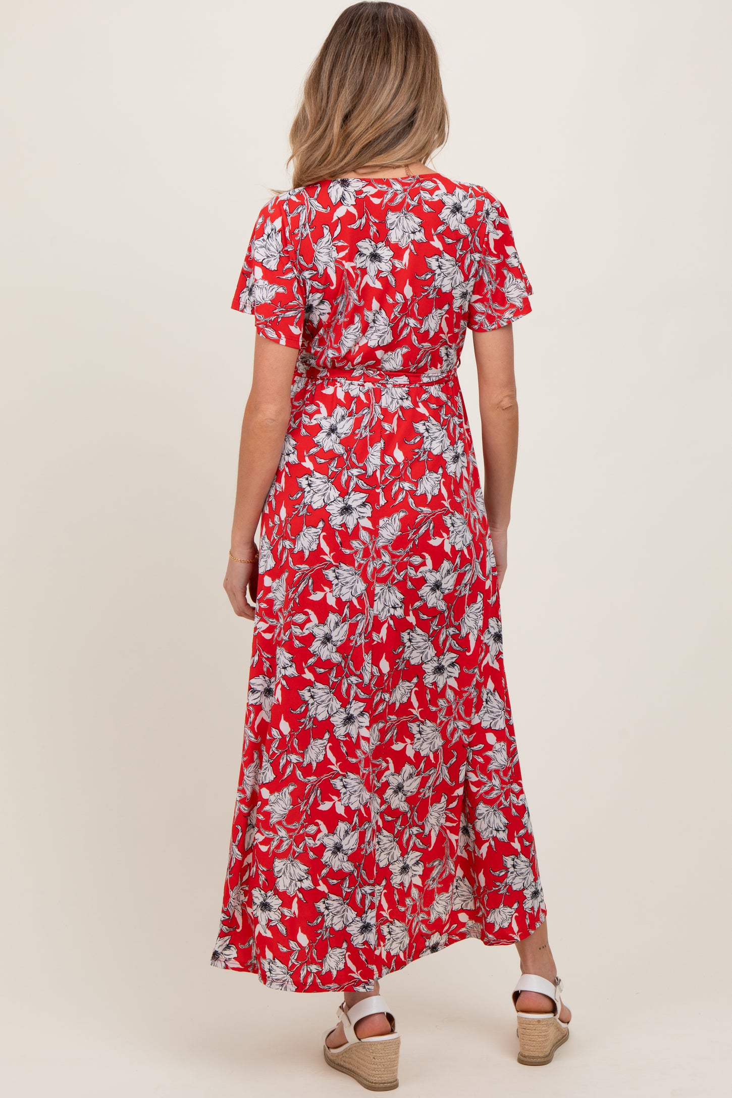 woman wearing a red floral maternity maxi dress, featuring short sleeves and a fitted waist, seen from the back