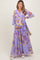 woman wearing a purple floral maternity maxi dress and gently holding her baby bump