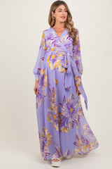 woman wearing a lavender floral maternity maxi dress with a wrap style and long sleeves, showcasing her baby bump