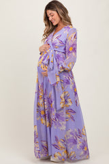 woman wearing a purple floral maternity maxi dress and gently holding her baby bump