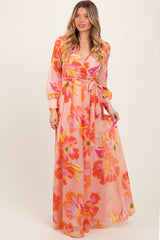 woman wearing a pink floral maxi dress with long sleeves and a tie waist detail