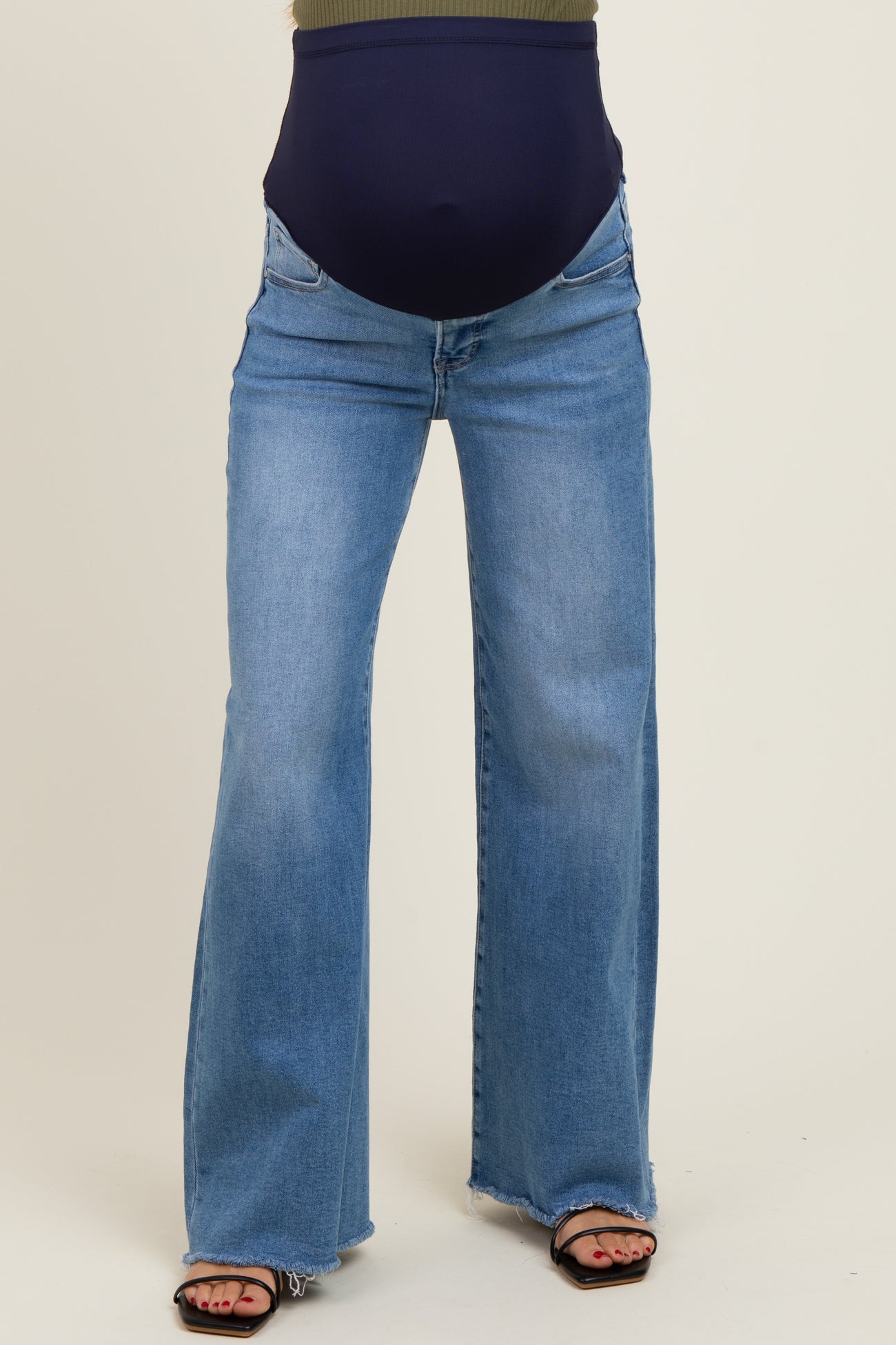 woman wearing a pair of light blue maternity flared jeans with a navy waistband and sandals