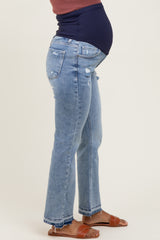 woman wearing distressed light blue maternity jeans with a navy blue over-the-bump panel and a baby bump visible