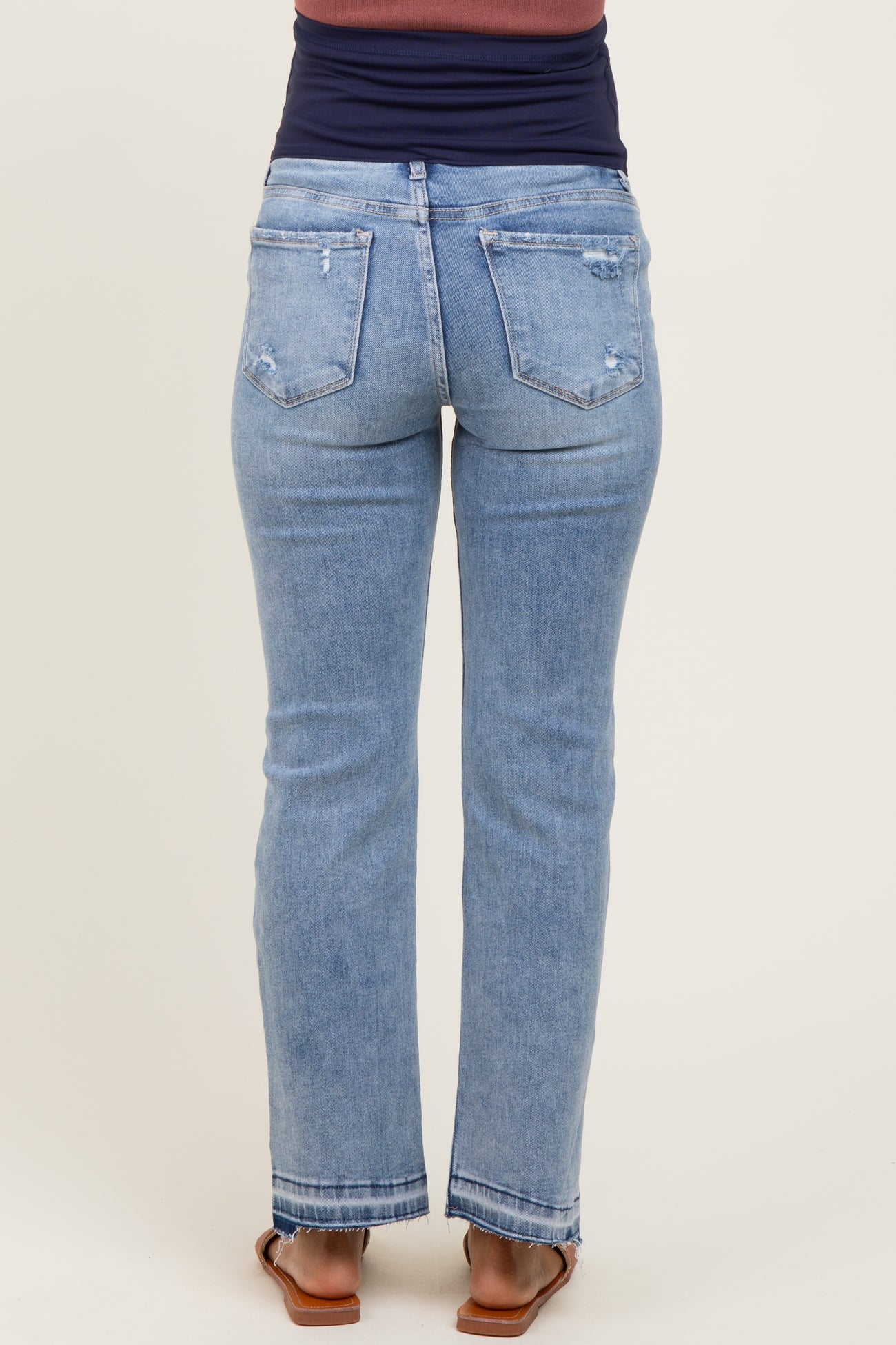 woman wearing light blue maternity straight leg jeans, showing the back view with distressed details