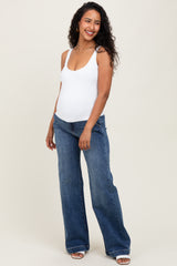 woman wearing a white maternity bodysuit and blue wide-leg jeans, showing her baby bump