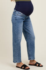 woman wearing blue maternity jeans with a visible baby bump, paired with black sandals