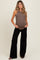 woman wearing a brown maternity tank top and black wide-leg pants, showing her baby bump